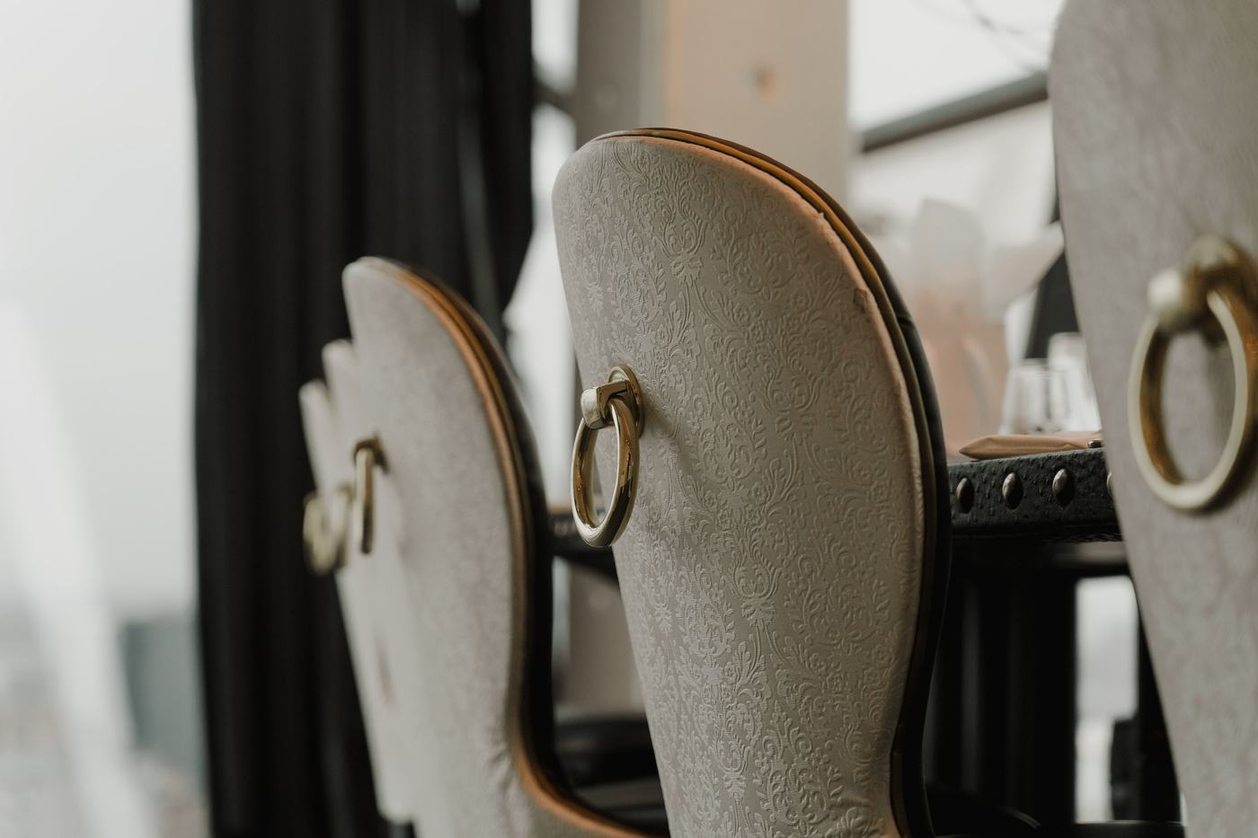 Ivory damask dining chairs with gold ring handles at a wedding table