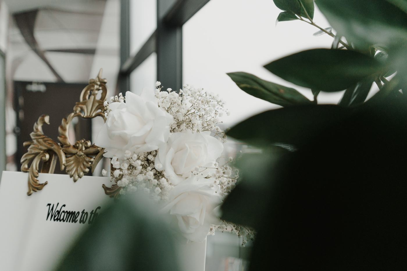 White roses and gypsophila beside a welcome sign on a gilded easel